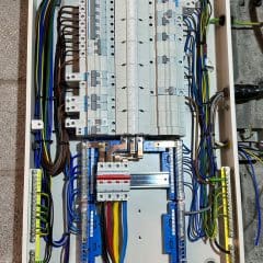 An open electrical panel with multiple circuit breakers, wires, and connectors neatly arranged inside. The panel includes various colored wires indicating different phases or functions, with labels and terminals visible. The setup appears to be for an industrial or commercial application.